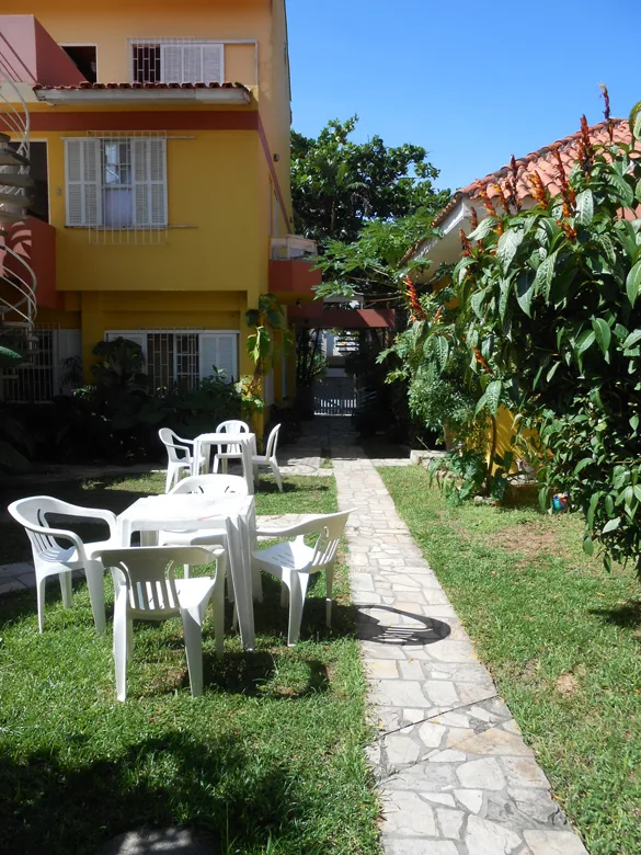 Jardín de la posada Casas Amarelas con mesas, césped y las casas amarillas